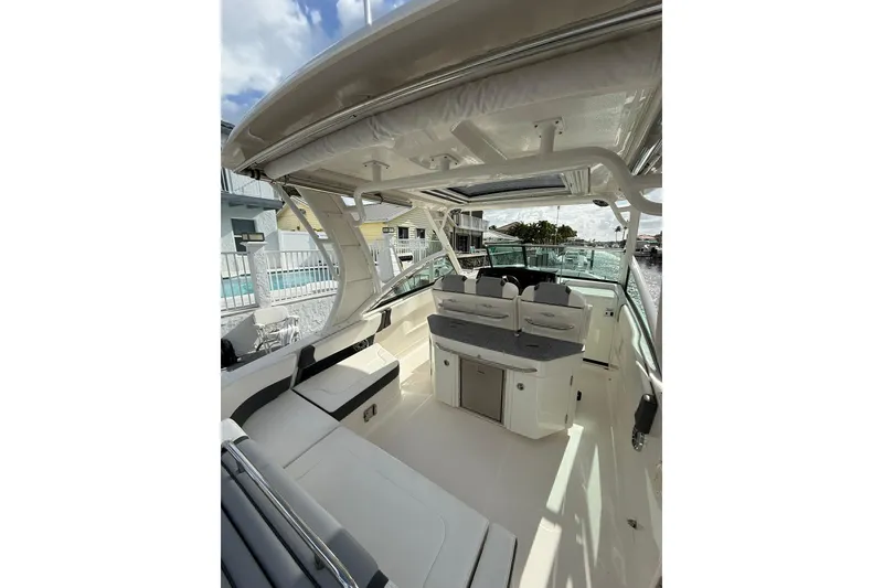 Slide: The Image of 2023 Chaparral 300 OSX boat interior with seating and helm, under a clear sky. - 16