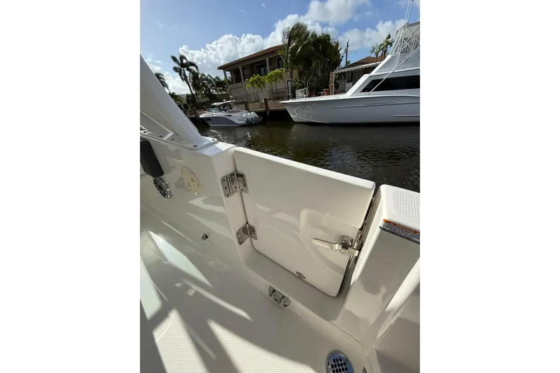 Slide: The Image of 2023 Chaparral 300 OSX boat docked near waterfront homes under a clear sky. - 18