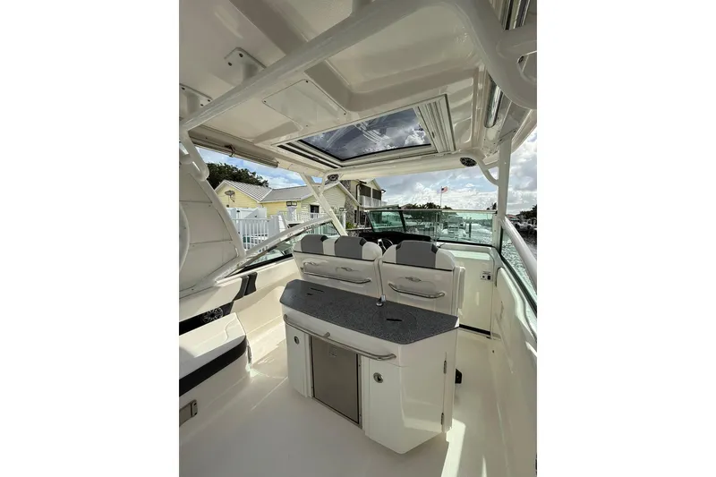 Slide: The Image of 2023 Chaparral 300 OSX boat interior with seating and countertop under a sunroof. - 19