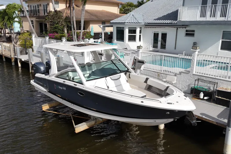 Slide: The Image of 2023 Chaparral 300 OSX boat docked by waterfront home with pool. - 2