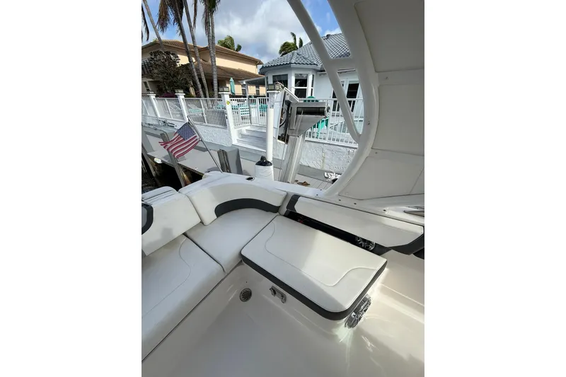 Slide: The Image of 2023 Chaparral 300 OSX boat interior with seating, docked near waterfront homes. - 21