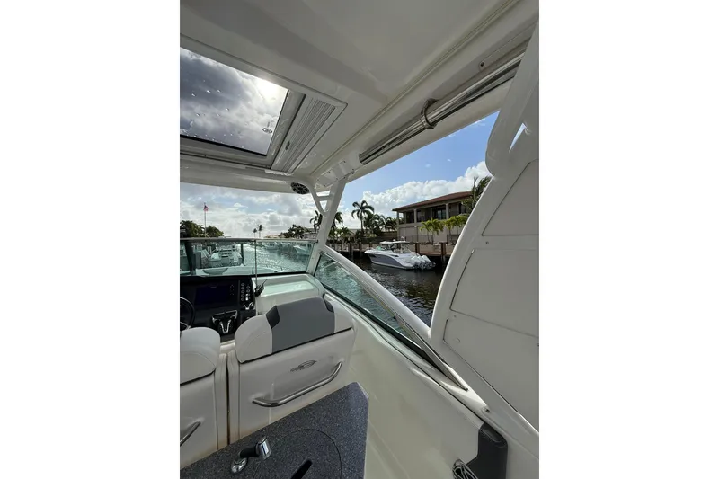 Slide: The Image of Interior view of 2023 Chaparral 300 OSX boat with open sunroof and waterfront scenery. - 23
