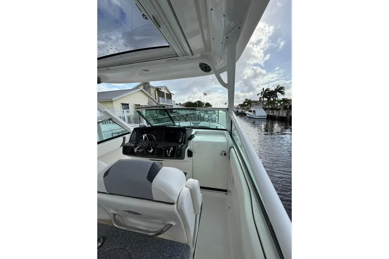 Slide: The Image of 2023 Chaparral 300 OSX boat interior with helm, docked by waterfront homes. - 27