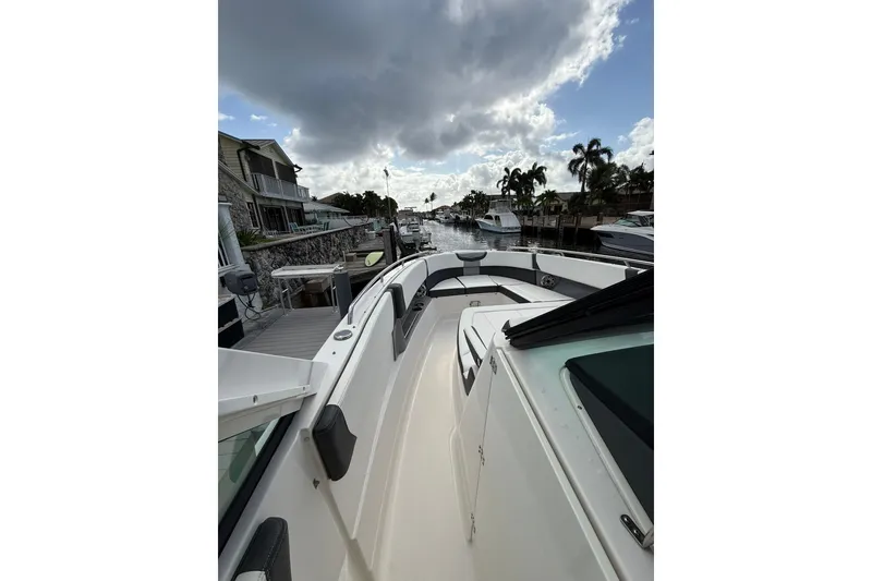 Slide: The Image of 2023 Chaparral 300 OSX boat docked by waterfront homes under cloudy sky. - 40