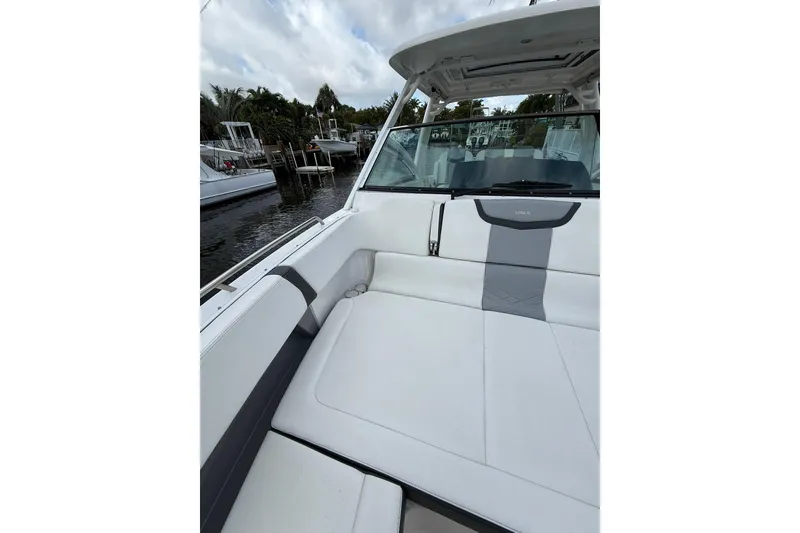 Slide: The Image of 2023 Chaparral 300 OSX boat interior with white seating, docked by the water. - 47