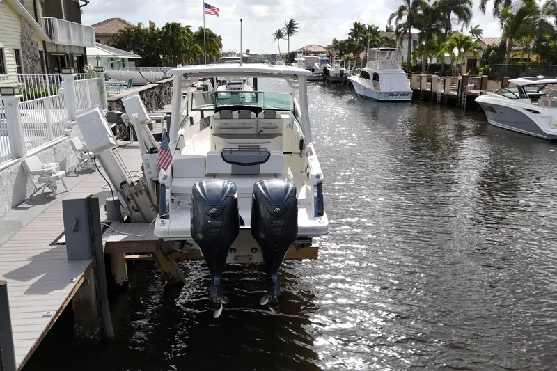 Slide: The Image of 2023 Chaparral 300 OSX boat docked in a sunny canal with palm trees. - 5