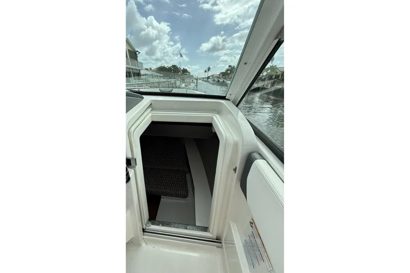 Slide: The Image of 2023 Chaparral 300 OSX boat interior with open cabin door, dockside view. - 52