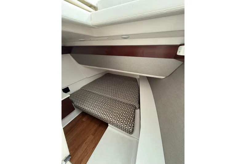 Slide: The Image of 2023 Chaparral 300 OSX cabin interior with patterned bedding and wood accents. - 53