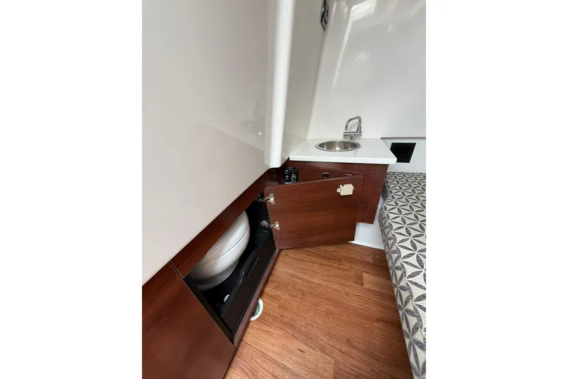 Slide: The Image of 2023 Chaparral 300 OSX interior with sink, wooden cabinetry, and patterned seating. - 57