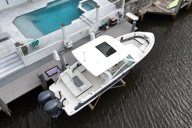 Slide: The Image of 2023 Chaparral 300 OSX boat docked near a poolside deck. - 6