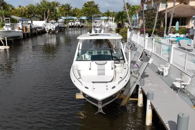 Slide: The Image of 2023 Chaparral 300 OSX boat docked in a scenic marina with palm trees. - 9