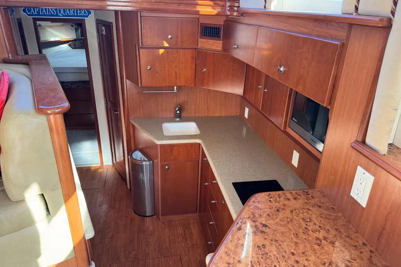 Slide: The Image of Interior of 2008 Silverton 42 Convertible yacht with wooden cabinetry and compact kitchen area. - 11