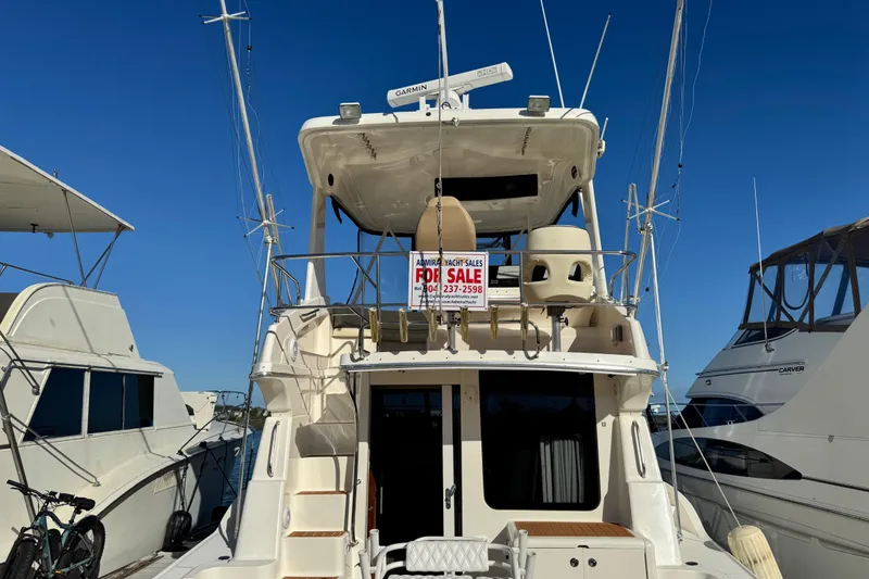 Slide: The Image of 2008 Silverton 42 Convertible yacht for sale, docked between other boats under clear blue sky. - 5