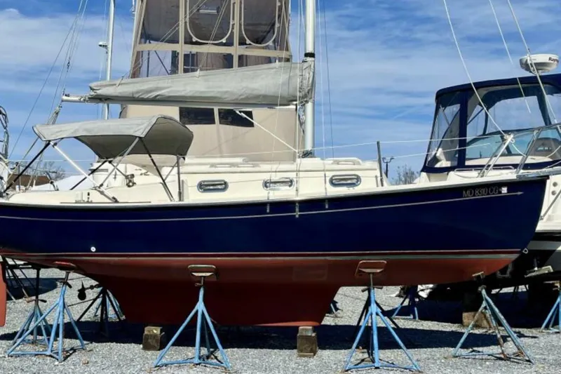 Slide: The Image of 2017 Com-Pac 23/IV sailboat on stands, blue hull, beige deck, marina background. - 6