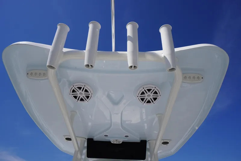 Slide: The Image of 2025 Tidewater 210 CC Adventure boat top view with rod holders and speakers against blue sky. - 16