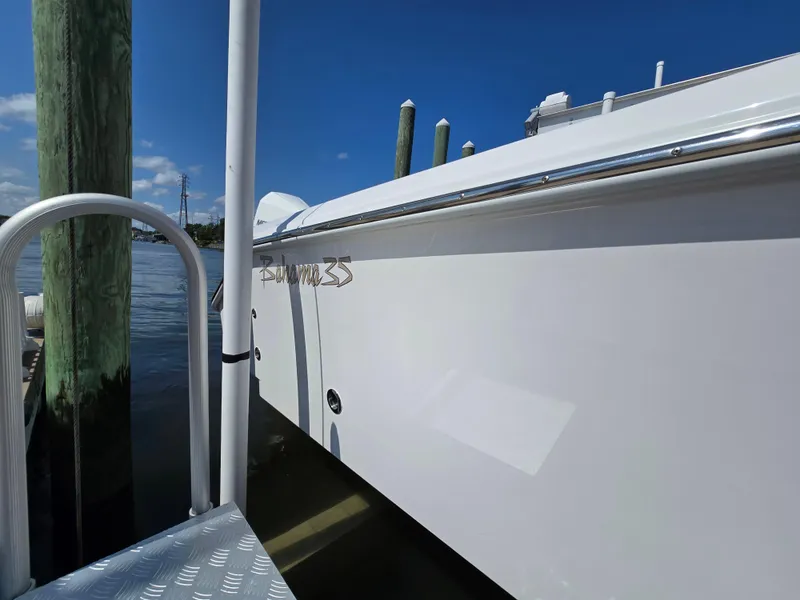 Slide: The Image of 2025 Bahama 35 Super Center Console docked by wooden posts, clear blue sky. - 18
