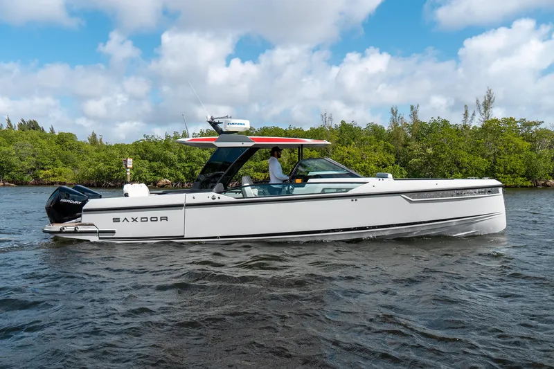 The Image of 2024 Saxdor 320 GTO boat cruising on a river with lush greenery in the background. - 0
