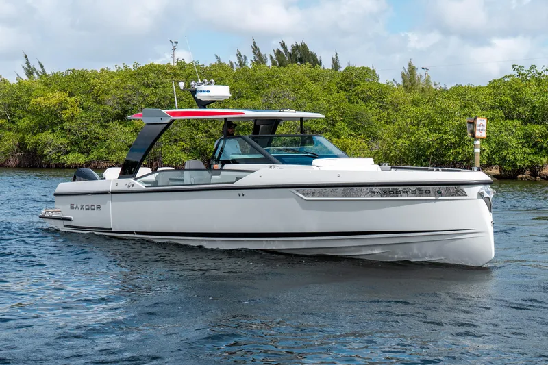 Slide: The Image of 2024 Saxdor 320 GTO boat cruising on a scenic waterway with lush greenery. - 2