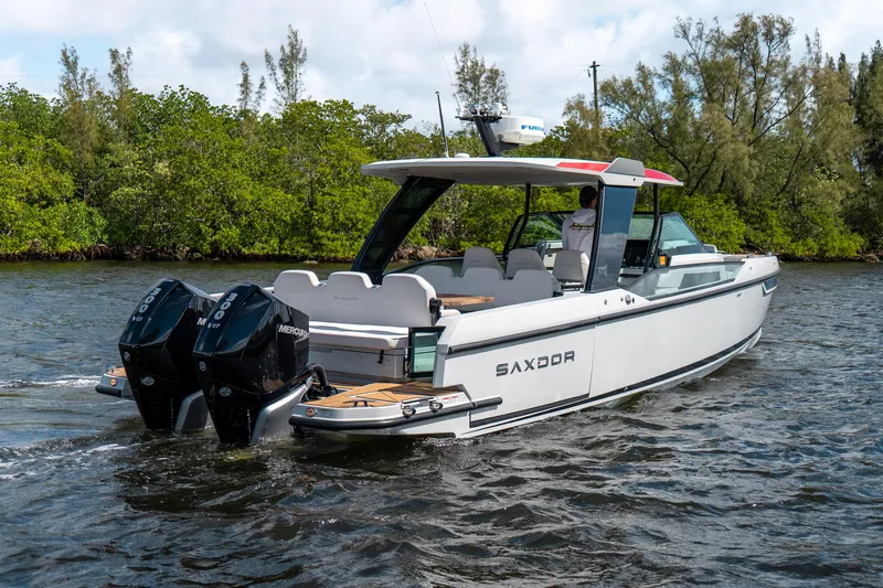 Slide: The Image of 2024 Saxdor 320 GTO boat cruising on a river with twin Mercury engines. - 3