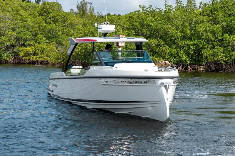 Slide: The Image of 2024 Saxdor 320 GTO boat cruising on a scenic waterway with lush greenery. - 5