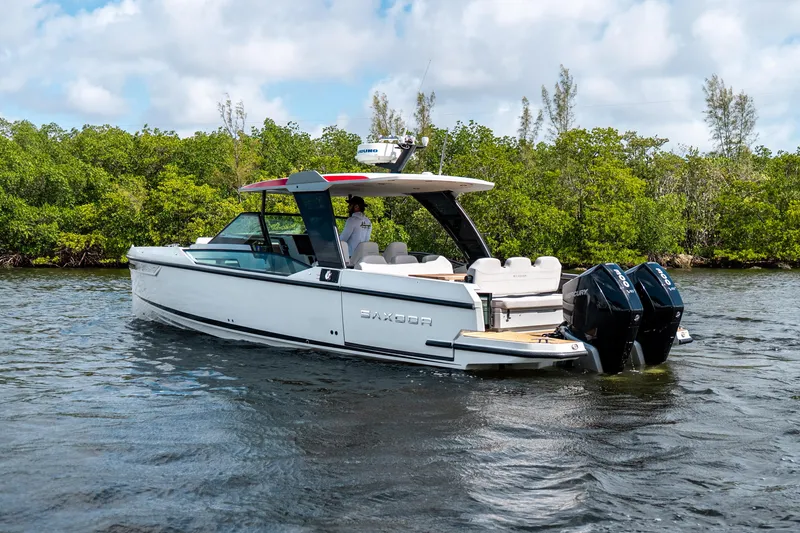 Slide: The Image of 2024 Saxdor 320 GTO boat cruising on a scenic waterway with lush greenery. - 7