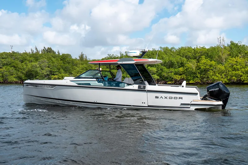 Slide: The Image of 2024 Saxdor 320 GTO boat cruising on a river with lush greenery in the background. - 8