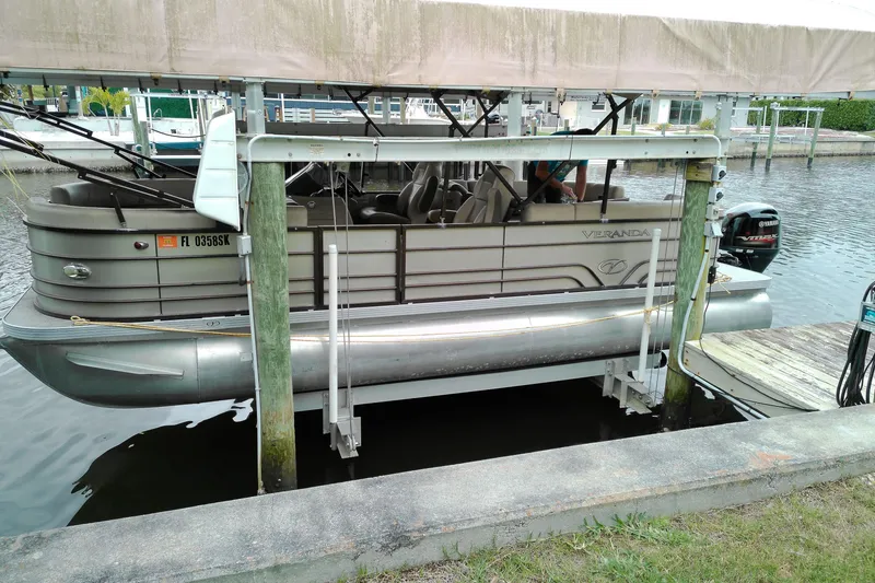 The Image of 2016 Veranda Relax V2275RC pontoon boat docked on a lift by the water. - 0