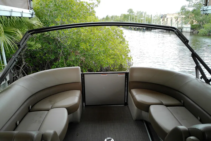 Slide: The Image of 2016 Veranda Relax V2275RC pontoon boat interior with plush seating, near lush greenery and waterway. - 11