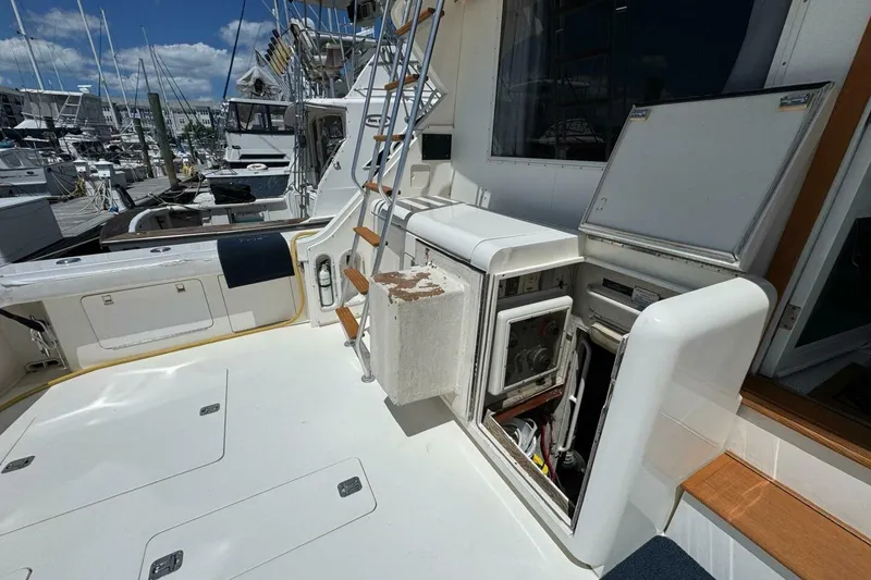 Slide: The Image of 1989 Bertram 50 Convertible yacht deck with open storage compartments and marina view. - 16