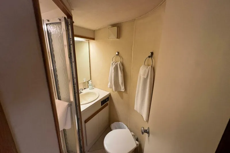 Slide: The Image of Compact bathroom in a 1989 Bertram 50 Convertible yacht, featuring sink, shower, and towels. - 6