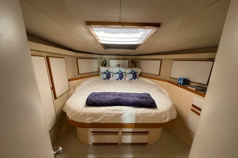 Slide: The Image of Cozy bedroom interior of 1989 Bertram 50 Convertible yacht with skylight and plush bedding. - 8