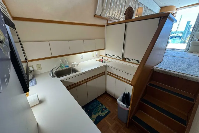 Slide: The Image of 1989 Bertram 50 Convertible yacht kitchen with white cabinets and wooden accents. - 9