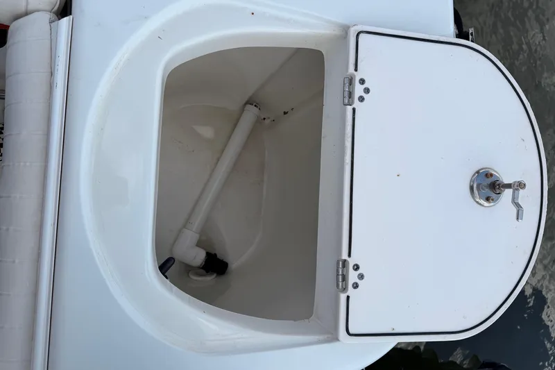 Slide: The Image of Open storage compartment on a 2005 Sailfish 236 CC boat, featuring a white interior and pipe. - 13
