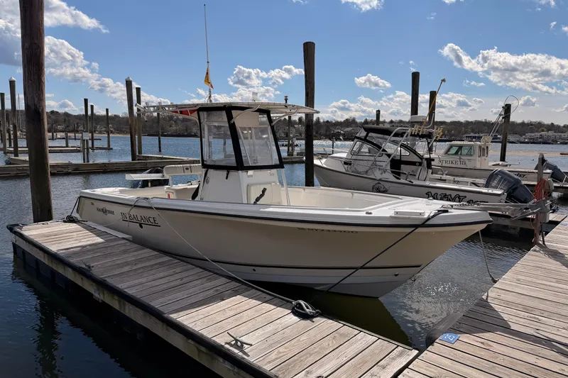 Slide: The Image of 2005 Sailfish 236 CC boat docked at marina under blue sky. - 2