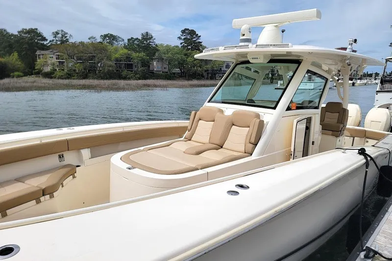 Slide: The Image of 2018 Scout 355 LXF boat with luxurious seating, docked by a scenic waterfront. - 10
