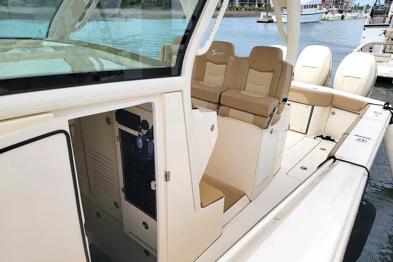 Slide: The Image of 2018 Scout 355 LXF boat interior with beige seating and open storage compartment. - 12