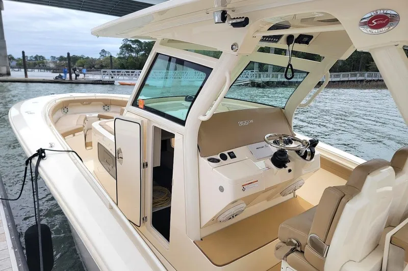 Slide: The Image of 2018 Scout 355 LXF boat docked, showcasing helm and seating area. - 16