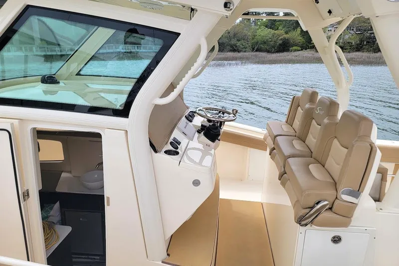 Slide: The Image of 2018 Scout 355 LXF boat interior with helm, seating, and cabin view. - 19