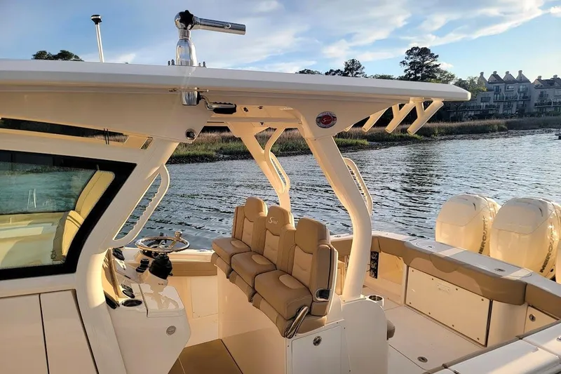 Slide: The Image of 2018 Scout 355 LXF boat interior with seating and helm, docked by the water. - 2