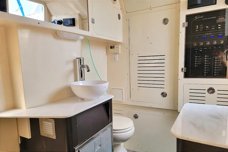 Slide: The Image of Interior of 2018 Scout 355 LXF boat featuring a modern bathroom with sink and control panel. - 21