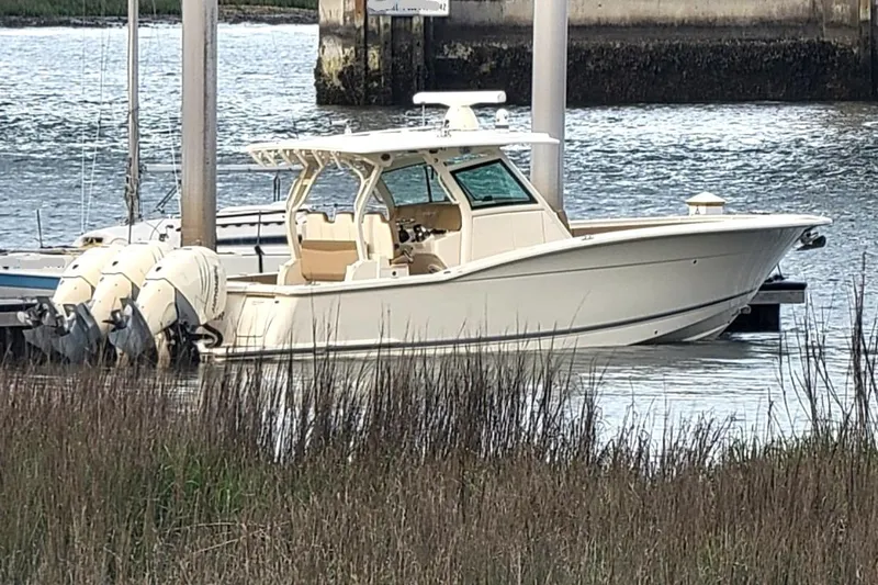 Slide: The Image of 2018 Scout 355 LXF boat docked by the water with triple outboard engines. - 24