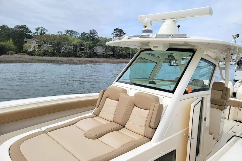 Slide: The Image of 2018 Scout 355 LXF boat with luxurious seating on a serene waterway. - 25