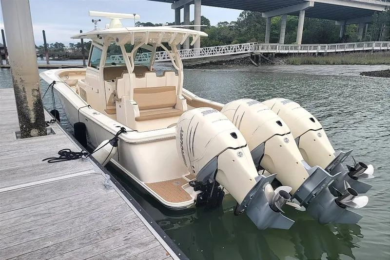 Slide: The Image of 2018 Scout 355 LXF boat docked with triple outboard engines, under a bridge. - 28