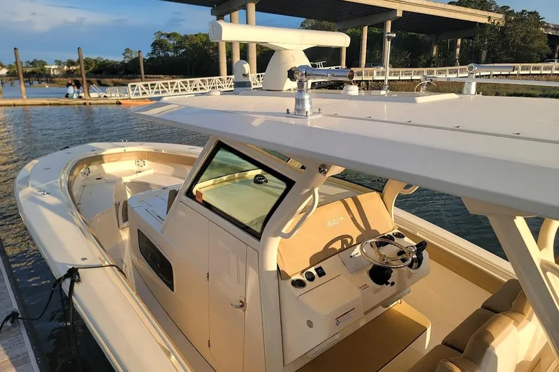 Slide: The Image of 2018 Scout 355 LXF boat docked by a scenic waterfront under a bridge. - 32