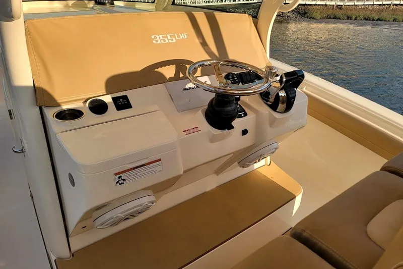 Slide: The Image of 2018 Scout 355 LXF boat helm with steering wheel and controls, docked by the water. - 37