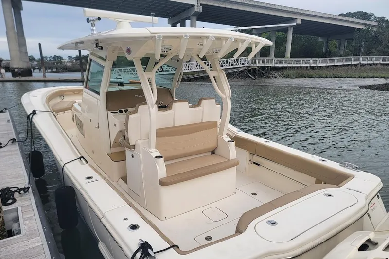Slide: The Image of 2018 Scout 355 LXF boat docked near a bridge, featuring spacious seating and sleek design. - 44