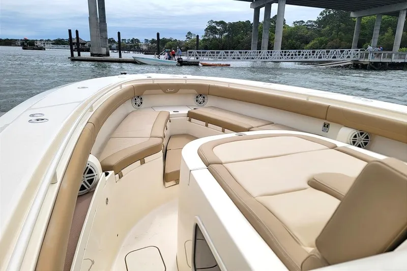 Slide: The Image of 2018 Scout 355 LXF boat with tan seating, docked near a bridge. - 5