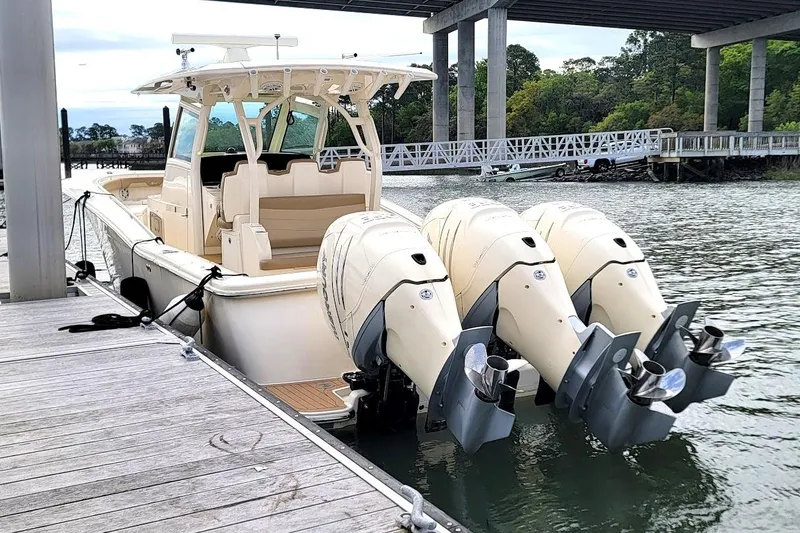 Slide: The Image of 2018 Scout 355 LXF boat docked with triple outboard engines under a bridge. - 6