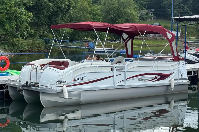 The Image of 2007 JC SunToon 23TT pontoon boat with red canopy docked on a calm lake. - 0