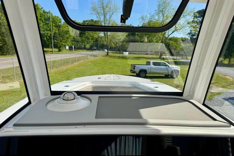 Slide: The Image of 2024 Sea Hunt Gamefish 28 Coffin Box interior view through windshield, parked outdoors. - 16